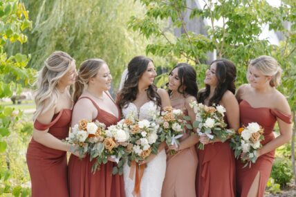 A bride and her bridesmaids holding flower bouquets in The Gardens at Pillar and Post.
