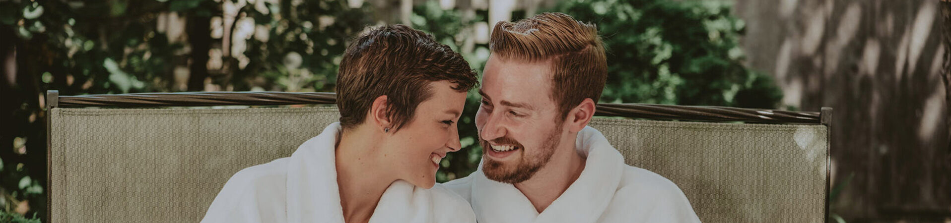 A couple in spa robes looking at eachother.